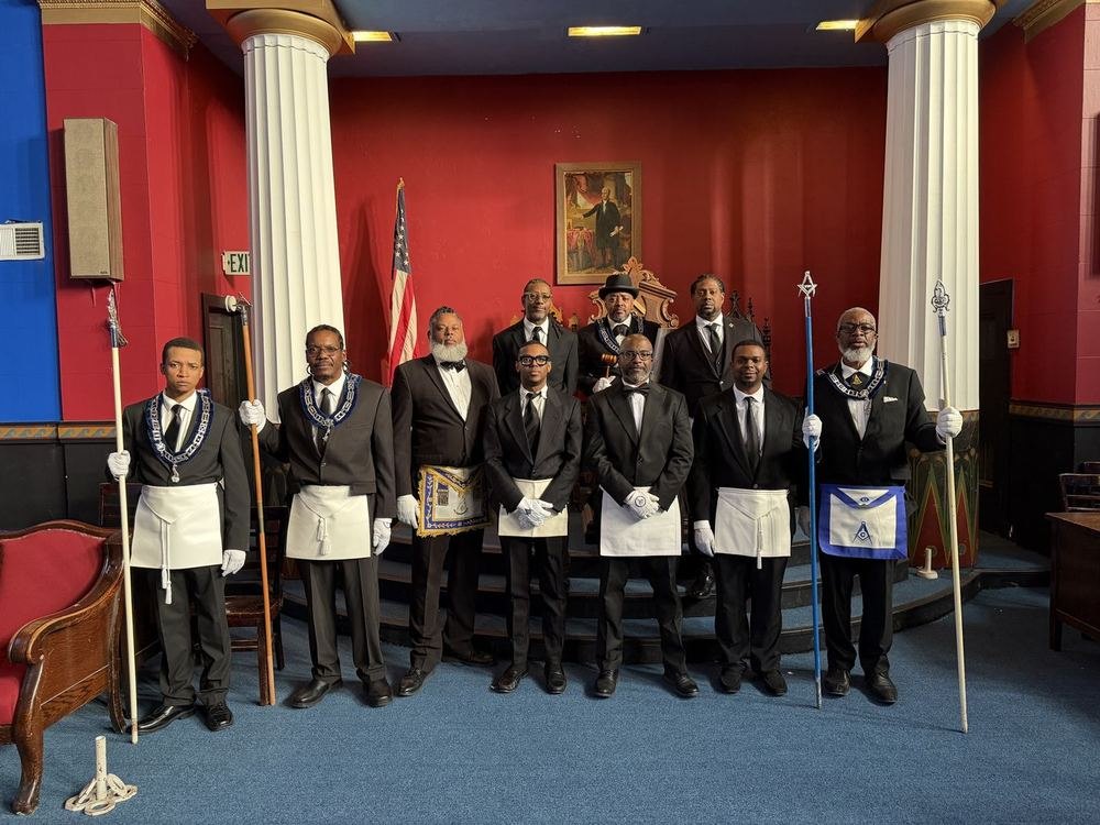 Nine brethren of Waterford Lodge No. 13 in formal dress with Masonic aprons, collars and jewels, standing together in the lodge room.