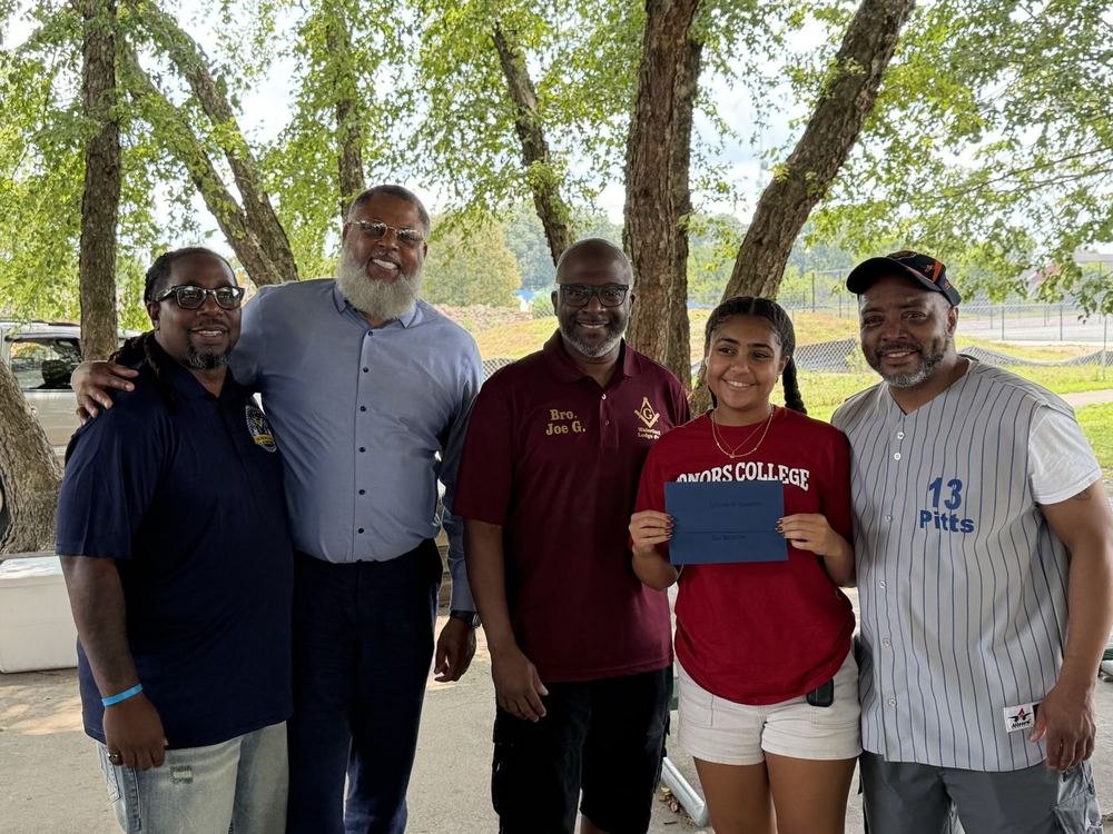 Brethren of the lodge presenting a scholarship award to a student at an outdoor event.